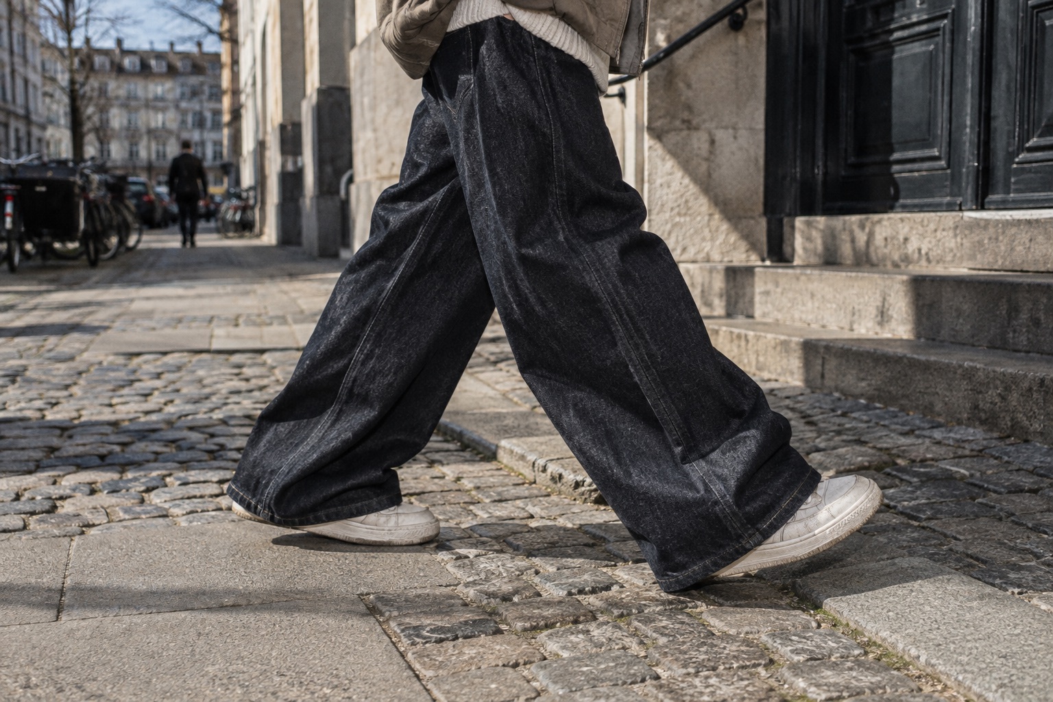 Mørke baggy jeans og sneakers i bevægelse på en gade i København