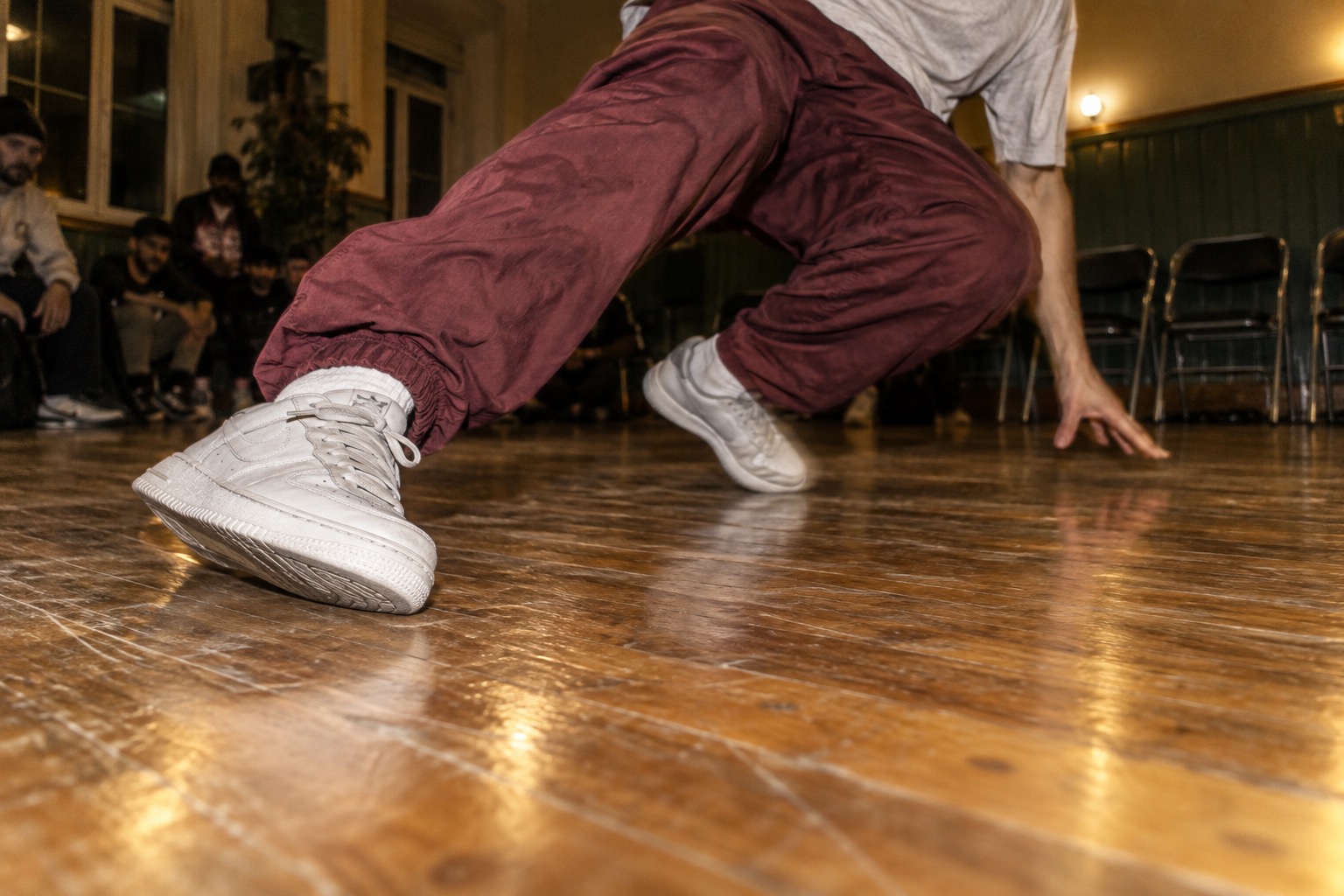 Breakdancer viser hurtigt fodarbejde i en sal med trægulv