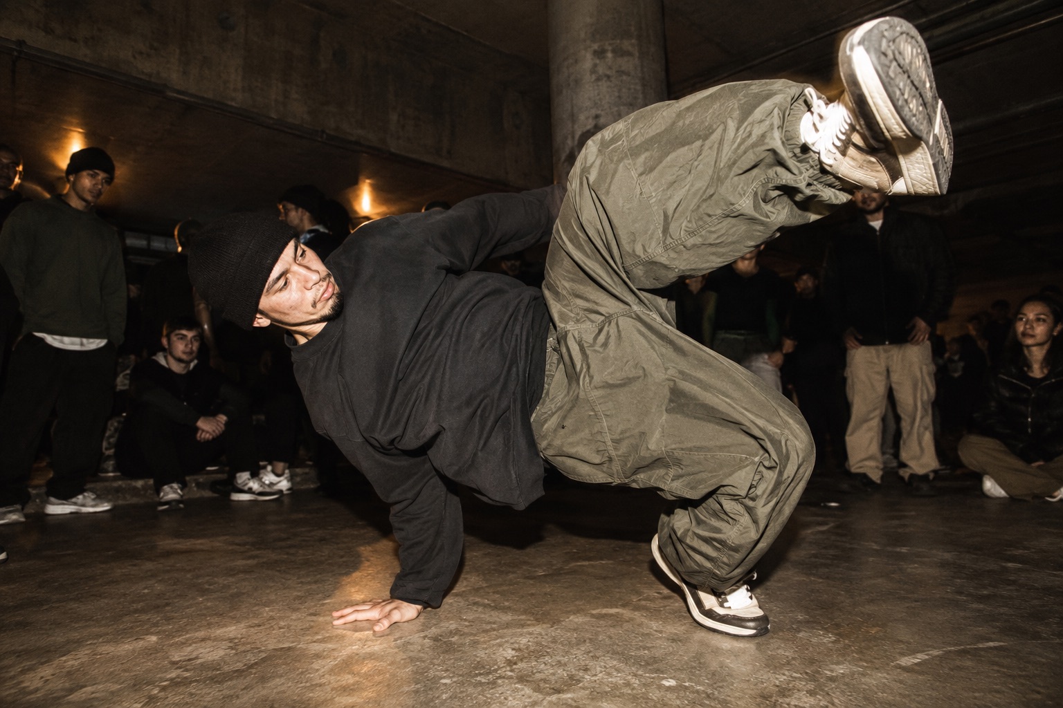 Danser i rummeligt streetwear laver en freeze i et råt lokale